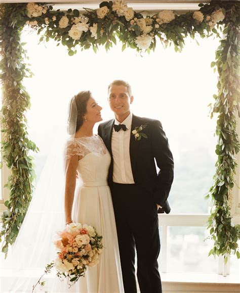 Classic New York bride and groom pose beneath floral adorned arbor