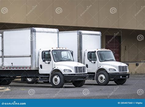 Compact Day Cab Middle Duty White Rigs Semi Trucks With Long Box Trailers Loading Cargo Standing