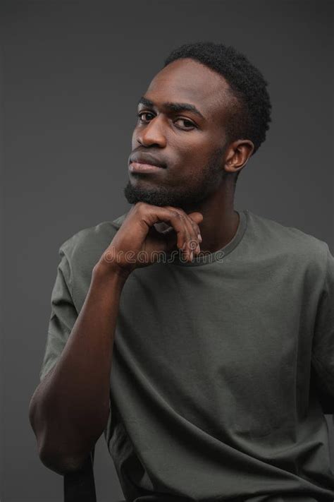 Pensive Black Guy Sitting On Chair Against Gray Background Stock Image