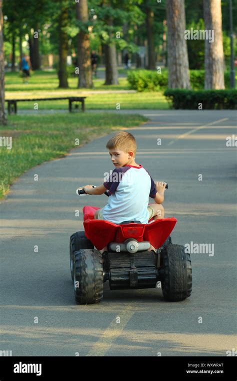 Boy riding big red toy car in park, back view Stock Photo - Alamy