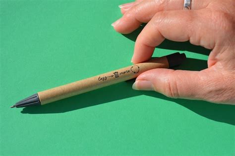 Premium Photo Close Up Of Hand Holding Pen Against Green Background