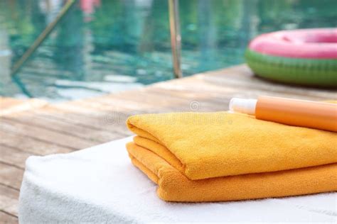 Beach Towels And Sunscreen On Sun Lounger Near Outdoor Swimming Pool At