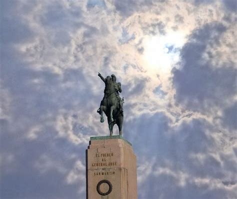 There Is A Statue On Top Of A Building With Clouds In The Background