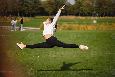 Sport girl jumping in the air on nature demonstrate perfect stretching