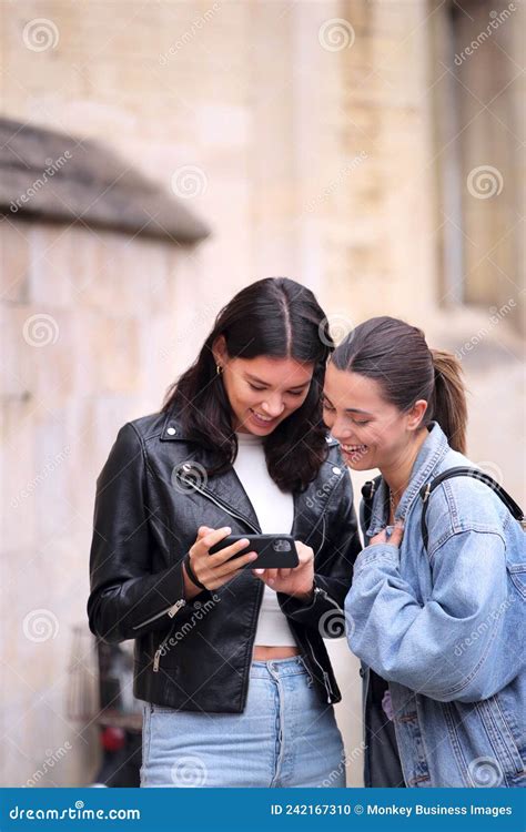 Same Sex Female Couple Sightseeing Looking At Mobile Phone And Walk