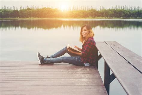 Premium Photo Portrait Of Smiling Woman Holding Book While Sitting On