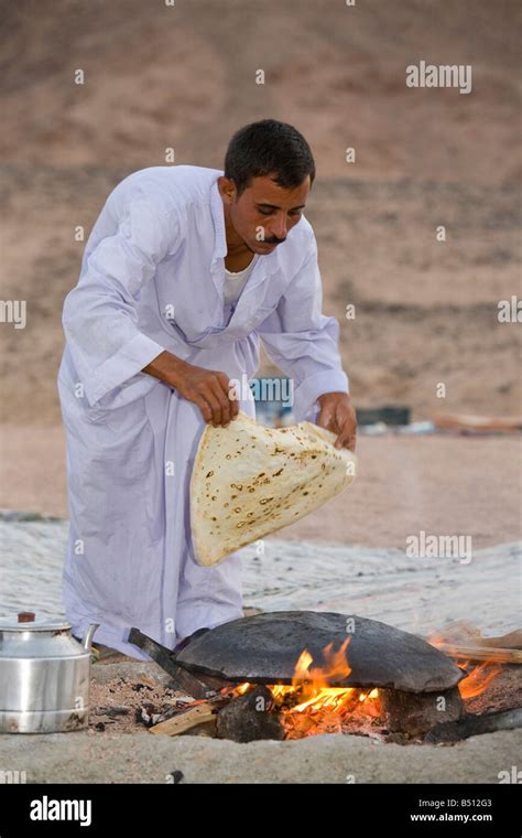 A Bedouin Man Cooking Bread On An Open Fire In A Camp In The Sinai