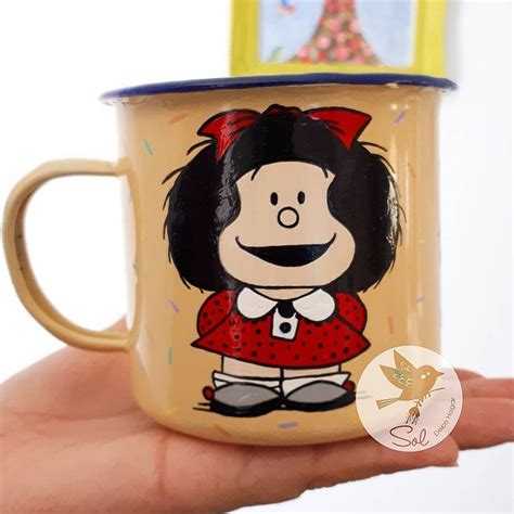 A Hand Holding A Yellow Coffee Mug With A Cartoon Character On It