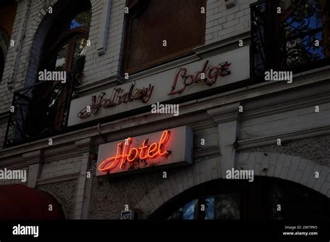 Red Neon Hotel Sign Glowing During The Day Over A European Looking