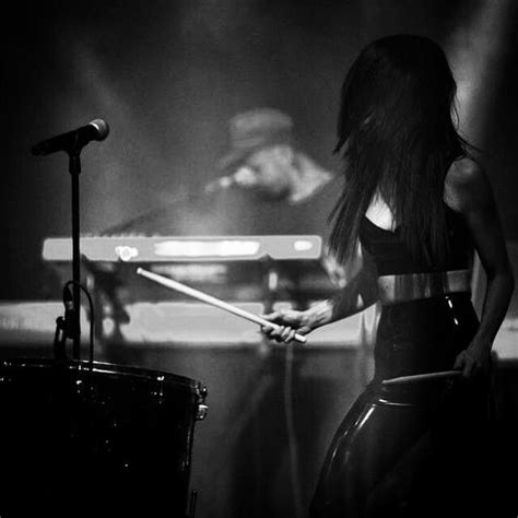 A Woman With Long Hair Playing Drums In Front Of A Microphone And