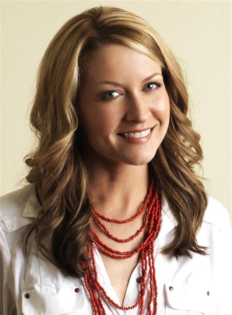 a woman in a white shirt is smiling and wearing red beads on her necklaces