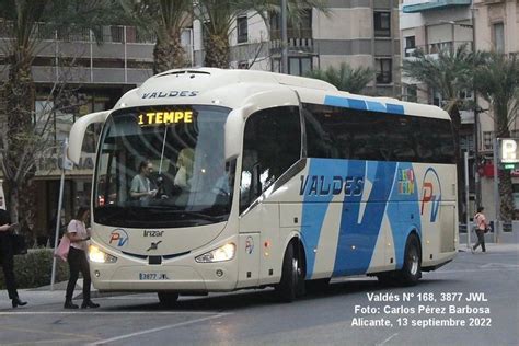 A White And Blue Bus Driving Down A Street Next To Tall Buildings With