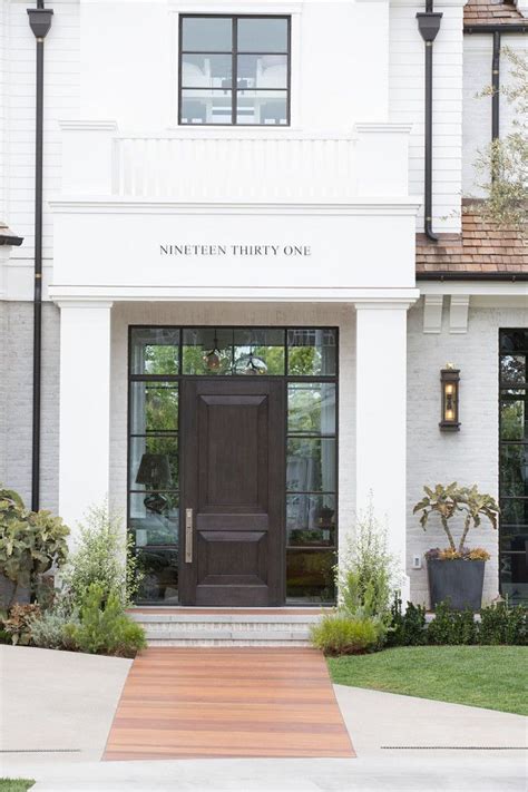 The Front Entrance To A White Brick Building With Black Doors And