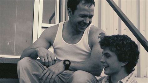 a man sitting next to a young boy on the steps smiling at eachother