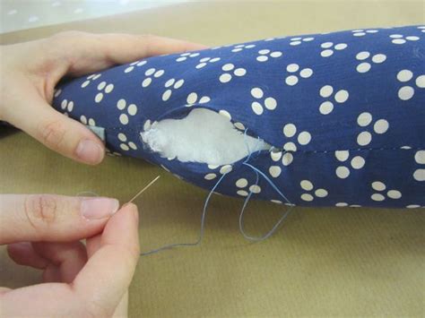 Someone Is Sewing Something On A Pillow With Blue And White Polka Dot