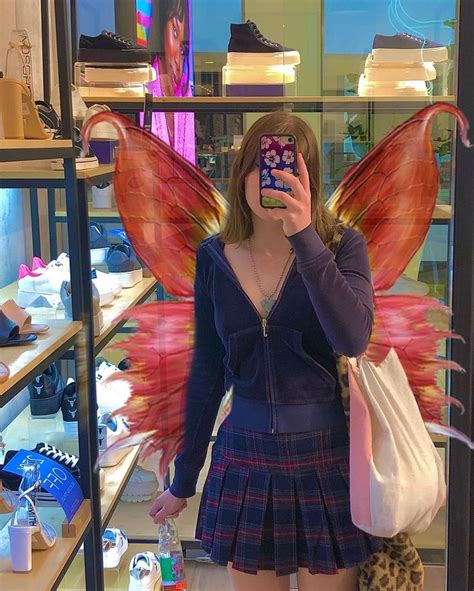 A Woman Taking A Selfie In Front Of A Store Window With An Angel Wings Costume