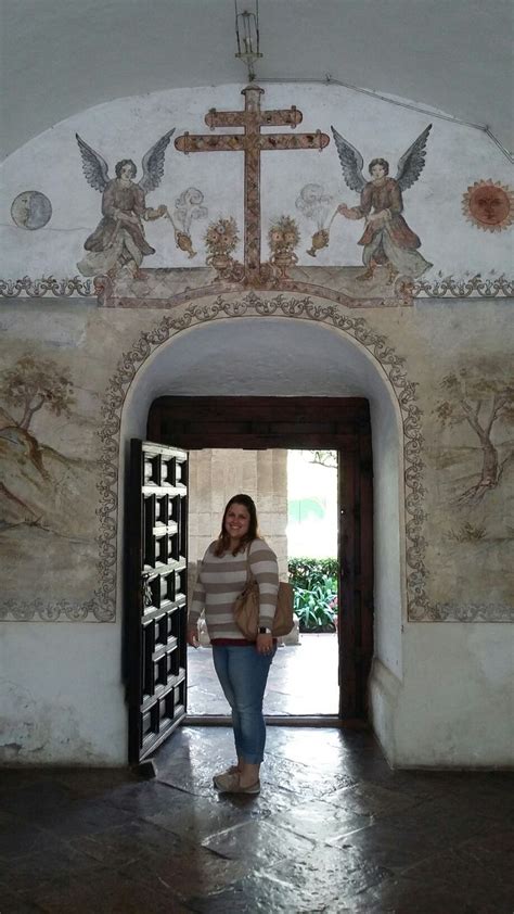 A Woman Standing In Front Of A Doorway With Paintings On The Wall And