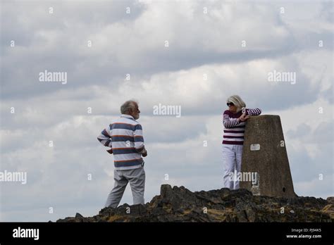 Two People Standing Next To The Trig Point At Beacon Hill