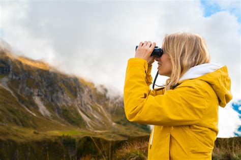 Mujer rubia joven haciendo senderismo en las montañas y mirando a