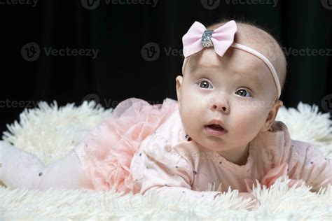 Beautiful baby girl in pink clothes on a black background. Baby at four ...