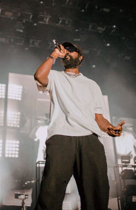 A Man Standing On Top Of A Stage Holding A Cell Phone To His Ear With