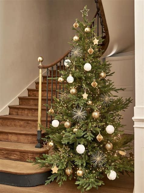 A Decorated Christmas Tree Sitting On Top Of A Wooden Floor Next To A Banister