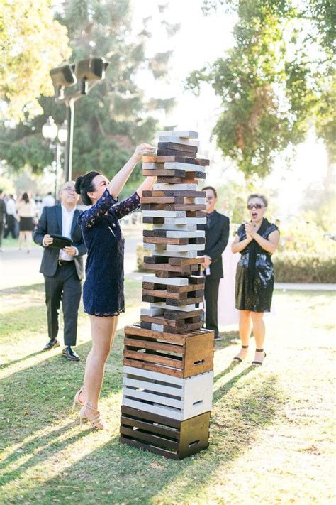 A Woman Standing Next To A Giant Stack Of Wooden Blocks On Top Of A