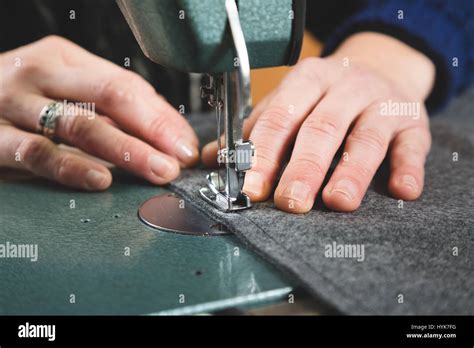 Hands Of Seamstress Sewing With A Professional Machine A Grey Fabric