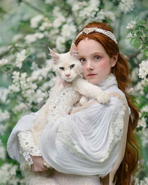 A Woman With Long Hair Holding A White Cat In Her Arms And Wearing A Tiara