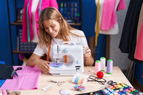 Young Blonde Girl Tailor Smiling Confident Using Sewing Machine At