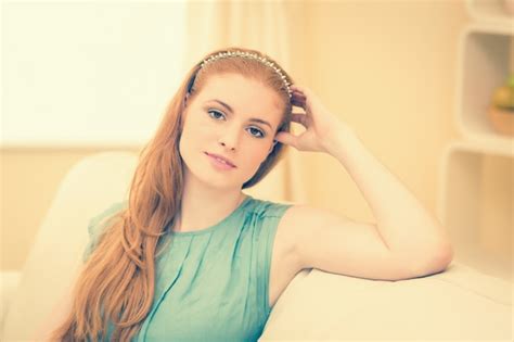 Premium Photo Thoughtful Redhead Sitting On The Couch Smiling At Camera