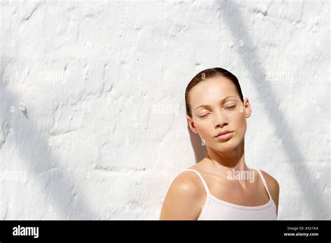 A Young Woman Leaning Against A Wall Eyes Closed Stock Photo Alamy