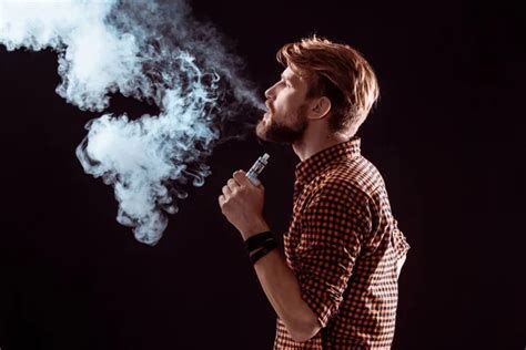 Young man vaping e-cigarette with smoke on black Stock Photo by ©Milkos ...