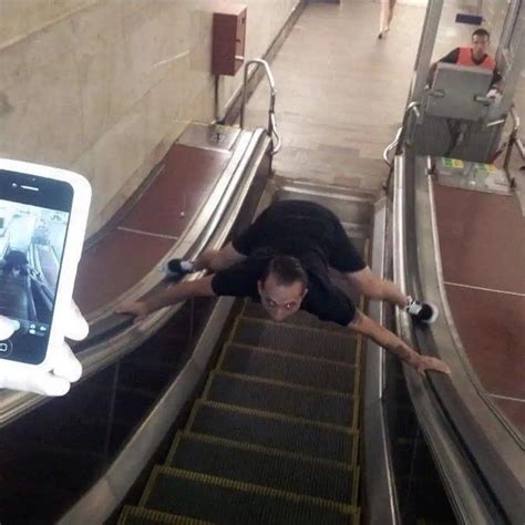 A Man Falling Down An Escalator While Using His Cell Phone To Take Pictures