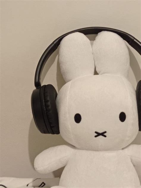 A White Stuffed Rabbit With Headphones On Its Ears Sitting In Front Of