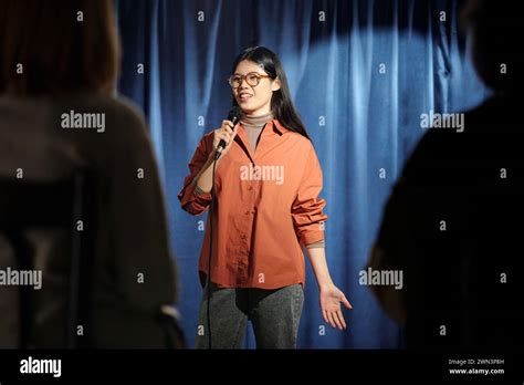 Young Female Comedian Of Stand Up Club Standing On Stage With Blue