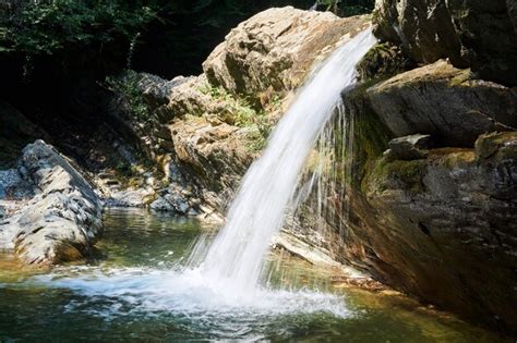 Uma pequena cachoeira limpa cai de uma saliência rochosa em um vale