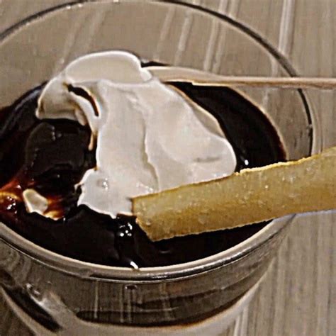 a glass filled with ice cream, chocolate sauce and a piece of bread on ...