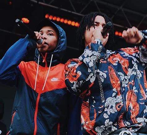 Two Young Men Standing Next To Each Other On Stage With Microphones In