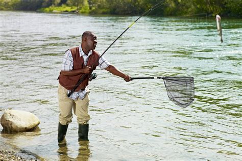 Black Man With Net Catching Fish In Stream Stock Photo Dissolve