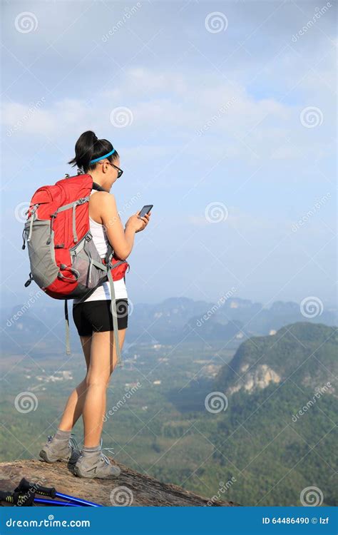 Caminhante Da Mulher Que Usa O Telefone Celular No Pico De Montanha