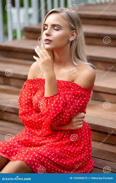 Tender Blonde Model With Naked Shoulders Wearing Red Dress Posing On The Wooden Staircase Stock