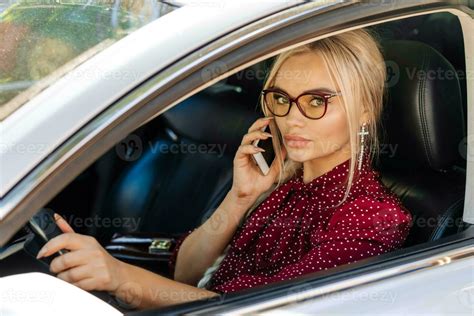 Portrait Of A Beautiful Blonde Woman In A Red Dress Sitting In A Car