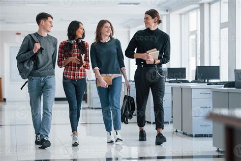 Four people. Group of young workers walking in the office at their