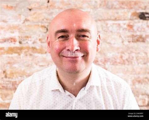 Portrait Of Bald Adult Mature Man With Emotions Against Brick Wall