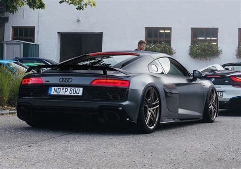 A Man Is Sitting In The Driver S Seat Of A Sports Car While Another One