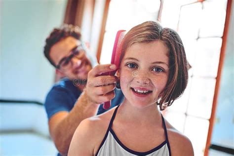 Getting Ready With Some Help From Dad A Father Combing His Little Daughters Hair At Home Stock