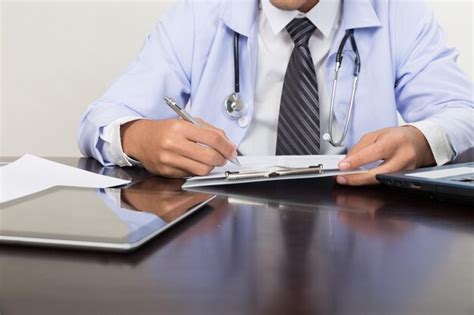 Premium Photo Midsection Of Doctor Writing Prescription On Paper With