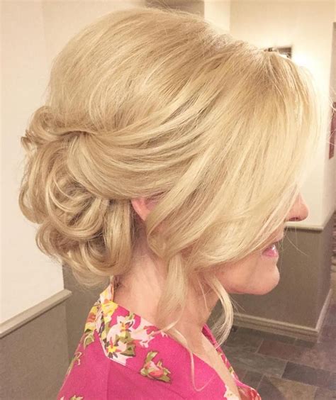 A Woman With Blonde Hair In A Pink Top Is Looking At Her Reflection In The Mirror