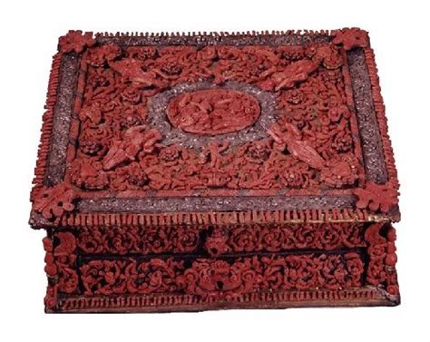 An Intricately Carved Wooden Box With Carvings On The Lid And Sides In Red